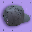 Load image into Gallery viewer, Centered close up of the vented back of the black 7-Strong script logo hat, this view shows it as a snapback and a lavender 7-bolt beside the snap. The hat is featured a deep lavender background with black 7-bolts patterned throughout.