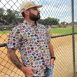 Load image into Gallery viewer, Man wearing a colorful patterned shirt and beige cap standing near a chain-link fence.