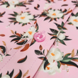 Load image into Gallery viewer, Midsection Close Up view of the "Magnolia PI" 7-Strong Adult button down shirt, featuring white and green magnolia flowers patterned all over a light pink background.