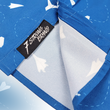 Load image into Gallery viewer, A sweep tag view of the adult 7-Strong "Paper Planes" button down shirt - featuring various sizes and designs of paper airplanes, some with dotted trails behind them against a royal blue background. The shirt is displayed against a faced background of the shirt details.