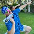 Load image into Gallery viewer, Male model and female child showcasing the adult 7-Strong "Paper Planes" button down shirt - featuring various sizes and designs of paper airplanes, some with dotted trails behind them against a royal blue background. Model is pointing towards skill, smiling at camera, as if aiming the paper airplane in is hand towards a location.