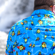 Load image into Gallery viewer, Back view of male model, facing away from camera, wearing the 7-Strong Avocado Coast button down featuring various avocado characters engaging in summer activities such as grilling, playing volleyball, weightlifting, surfing, etc against a blue shimmery wave looking background.