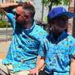 Load image into Gallery viewer, Male adult and male youth models wearing the 7-Strong Avocado Coast button down, sitting on a bench and looking in opposite directions.