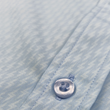 Load image into Gallery viewer, Close up mid button view of the baby blue long sleeve EveryWEAR adult button up. Pattern is subtle white 7-Bolts lined up all against each other across a baby blue background. The shirt is featured on a soft background of a wave hitting the beach.