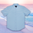 Load image into Gallery viewer, Full centered view of the baby blue short sleeve EveryWEAR adult button up. Pattern is subtle white 7-Bolts lined up all against each other across a baby blue background. The shirt is featured on a soft background of a wave hitting the beach.