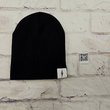 Load image into Gallery viewer, Full view of the black 7-Bolt beanie, rounded at the top and featuring a white 7-bolt tag in the bottom right corner of the cuff. Alongside is the reverse of the tag, featuring the 7-Strong QR Code. The beanie is featured against a white brick backdrop.