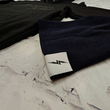 Load image into Gallery viewer, Angled view of the black 7-Bolt beanie, rounded at the top and featuring a white 7-bolt tag in the bottom right corner of the cuff. Alongside is the 7-Strong Midnight Hoodie. The beanie is featured against a white brick backdrop.
