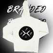 Load image into Gallery viewer, Full centered view of the back of the 7-Strong white 'Branded' hoodie, featuring a circle, badge-like design with two lightning bolts forming an X, and 7-Strong initials and established watermarks. Shirt is featured against a half black/half white background with the word "BRANDED" written three times down the middle.