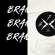 Load image into Gallery viewer, 3/4, left aligned view of the back of the 7-Strong white 'Branded' hoodie, featuring a circle, badge-like design with two lightning bolts forming an X, and 7-Strong initials and established watermarks. Hoodie is featured against a half black/half white background with the word "BRANDED" written three times down the middle.