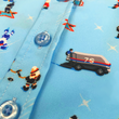 Load image into Gallery viewer, A close up midsection view of the youth 8-Bit Hat Trick button down - featuring various 8-bit inspired scenes from hockey games on a light blue ice-like background. The shirt is featured against a ice hockey floor with hats strewn about.