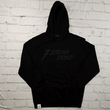 Load image into Gallery viewer, Full centered view of the 7-Strong Midnight Long Sleeve Hoodie, a black hoodie with black shadow font of the 7-Strong Brand logo. The hoodie is show against a white brick backdrop.