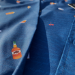 Load image into Gallery viewer, Midsection view of "Call Me Old Fashioned" adult long sleeve button-down. Features elements of an Old Fashioned cocktail (bottle of bourbon, glasses, oranges, stirrers, and ice) against a blue background which faintly spells out an Old Fashioned recipe.