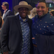 Load image into Gallery viewer, Male model posing with friend, smiling at camera wearing the "Call Me Old Fashioned" adult long sleeve button-down. Features elements of an Old Fashioned cocktail (bottle of bourbon, glasses, oranges, stirrers, and ice) against a blue background which faintly spells out an Old Fashioned recipe.