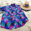 Load image into Gallery viewer, Full centered view of the 7-Strong "Neon Coast" adult button down shirt. Featuring vibrant teal, pink, and blue palm fronds, overlapping throughout the shirt, against a black/deep purple background. The shirt is laid out on the sand of a beach. Alongside the shirt is the 7-Strong "Neon Coast" Sun Hat, made from straw, which features the Neon Coast design in a patch on the front, with "7-Strong Brand" written across it. The pattern can also be seen lining the brim of the hat.