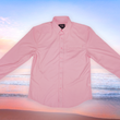Load image into Gallery viewer, Full centered view of the pink short sleeve EveryWEAR adult button up. Pattern is subtle white 7-Bolts lined up all against each other across a pink background. The shirt is featured on a soft background of a wave hitting the beach.