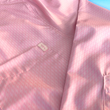 Load image into Gallery viewer, Close up pocket view of the pink long sleeve EveryWEAR adult button up. Pattern is subtle white 7-Bolts lined up all against each other across a pink background. The shirt is featured on a soft background of a wave hitting the beach.