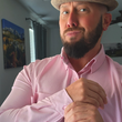 Load image into Gallery viewer, Medium view of a male model gazing into camera wearing the pink long short sleeve EveryWEAR adult button up. Pattern is subtle white 7-Bolts lined up all against each other across a pink background.