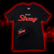 Load image into Gallery viewer, Full centered look at the Black 7-Strong Sideline Script tee, with white SEVEN and red scripted STRONG across the chest. Laid on top on the left side is the 7-Strong Sideline Script snapback hat, with the same features but as a puffed embroidery. Shirt and tee are on the back of a red and black fusion background.