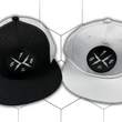 Load image into Gallery viewer, Both the black "Branded" trucker hat and the white "Branded" performance hat centered side-by-side against a white geometric background. Both feature raised black rubber X-Badge patches