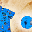 Load image into Gallery viewer, A 3/4 view of the 7-Strong "7-Seas" shirt, a bright blue colored shirt with various nautical depictions such as islands, ships, mermaids, etc - drawn in a treasure map like fashion. The shirt is displayed against a weathered treasure map and compass background. The bottom right features a detail circle with a close up of one of the shirt's drawings.