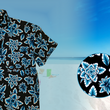 Load image into Gallery viewer, 3/4 view of the 7-Strong youth Electric Palms shirt, a collection of electric blue palm fronds featured against a black shirt. Shirt is displayed against a scenic beach background. Bottom right features a detail circle showing the design up close.