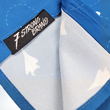 Load image into Gallery viewer, Bottom sweep tag view of the youth 7-Strong "Paper Planes" button down shirt - featuring various sizes and designs of paper airplanes, some with dotted trails behind them against a royal blue background. The shirt is displayed against a faced background of the shirt details.