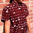 Load image into Gallery viewer, Medium close up of a youth male model against a brick wall wearing the 7-Strong youth "Smoke Show" button up, a deep maroon red colored shirt with rows of various barbecue and cookout related items and delicacies silhouetted in white.