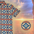 Load image into Gallery viewer, A short-sleeve button-down shirt featuring a bold Aztec-inspired pattern in shades of blue, orange, and cream. The intricate geometric design gives off a strong Southwest vibe. The shirt is set against a desert landscape background with towering red rock formations and a warm sunset sky, enhancing its rugged, adventurous aesthetic." Bottom right corner features a close up detail circle of the design itself.