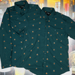 Load image into Gallery viewer, Full display view of the 7-Strong "Straight Sippin'" long sleeve and short sleeve button downs overlapping each other. The shirt is a deep green with black ripples as its background, while the foreground has various drinking glasses with various levels of whiskey, some with ice, others without. The shirt is shown against a background of various whiskies and bourbons on a shelf.
