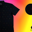 Load image into Gallery viewer, 3/4 view of short sleeve adult button down shirt, black as base color and adorned with multicolored version of our 7-Bolt design. Shirt is on a multicolor gradient-like background, in the upper right corner there is a circled out close up of the colored 7-bolts and on the bottom right, the logo for onePULSE Foundation, our cause collection partner.