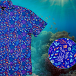 Load image into Gallery viewer, A 3/4 close-up shot of the 7-Strong "Coral of the Story" adult button down shirt. Color of the shirt is blue with vibrant purple, teal, orange sea life imagery - particularly fish and coral reef. The shirt is shown against an underwater background showcasing coral. In the bottom right corner is a close up circle highlight the shirt design details.