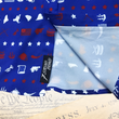 Load image into Gallery viewer, A close-up representation of 7-Strong's 1776 button down shirt, in the sweep tag region, against a Declaration of Independence background. Shirt is royal blue with stripes of various Americana icons, including the original 13 colonies and revolutionary war items.