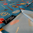 Load image into Gallery viewer, Sweep tag view of the 7-Strong "TLC OMG" shirt, a homage to wrestling objects featured all over the shirt including tables, ladders, chairs, ring bells, sledgehammers, brass knuckles, championships, guitars, stop signs, microphones amongst other items. The items are on a blue shirt with a faded steel cage background.