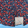 Load image into Gallery viewer, Bottom half sweep tag view of the 7-Strong "Aye Poppy" button down, featuring an array of red poppys with white sprigs on a deep navy blue shirt. The shirt is displayed against a partly cloudy sky.