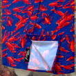 Load image into Gallery viewer, Close up view of the 7-Strong Dat Boil shirt sweep tag, along with design of shirt in deep navy blue with red crawfish patterned throughout overlapping one another. The shirt itself sits on a background image of items from a Crawfish Boil such as crawfish, seasoning, corn, and potatoes.