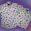 Load image into Gallery viewer, Full view of the 7-Strong Block Party adult and youth button downs overlapped on each other, featuring various colored blocks of different arrangements inspired by a classic video game, cascading down the shirt against a grayish background featuring shadows of the same shapes. The shirts are presented on a background of similar design.