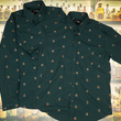 Load image into Gallery viewer, Full display view of the 7-Strong "Straight Sippin'" Short Sleeve and long-sleeve button downs, overlapping each other. The shirt is a deep green with black ripples as its background, while the foreground has various drinking glasses with various levels of whiskey, some with ice, others without. The shirt is shown against a background of various whiskies and bourbons on a shelf.