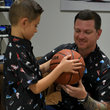 Load image into Gallery viewer, Father and son model shot, both wearing their version of the short sleeve "Got 'Em!" The button down features various athletic fashion sneakers in an 8-bit format arranged all over a black shirt. Both are admiring a basketball held by the child.