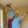Load image into Gallery viewer, Father and son model sporting the 7-Strong "Cheat Day" Shirts. Father has son on his shoulder in the air while the son holds cookie packages in his hand.