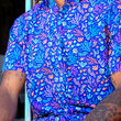 Load image into Gallery viewer, Mid torso shot of a male model wearing the 7-Strong "Coral of the Story" adult button down shirt. Color of the shirt is blue with vibrant purple, teal, orange sea life imagery - particularly fish and coral reef.