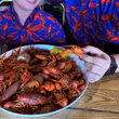 Load image into Gallery viewer, Foreground, a boil of crawfish with all the fixings, including potatoes and corn, with adult male model holding a crawfish beside a youth male model. Both are in the upper half, faces obscured, wearing the respective versions of the 7-Strong Dat Boil shirt in deep navy blue with red crawfish patterned throughout overlapping one another.