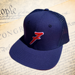 Load image into Gallery viewer, Full, slight overhead shot of the 7-Series trucker hat, showcasing its all navy blue look, back mesh panel, red puffed embroidered 7 with white outline, against a background of the Declaration of Independence.