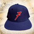 Load image into Gallery viewer, Full, head-on shot of the 7-Series trucker hat, showcasing its all navy blue look, solid front panels, red puffed embroidered 7 with white outline, against a background of the Declaration of Independence.