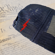 Load image into Gallery viewer, Back mesh panels view of 7-Series Red, White, and Blue trucker hat, featuring a red 7-Bolt logo on the side beside the snapback. Hat is shown against backdrop of the Declaration of Independence.