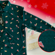 Load image into Gallery viewer, 3/4 full view of the long-sleeve 7-Strong "Oh, Christmas Treat" shirt - a green, christmas sweater-like background with columns of various white Christmas tree shaped cakes with red garland, some whole, some bitten. The shirt is displayed against a red, snowing background with a similar parted cake.