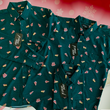 Load image into Gallery viewer, Full view of the long-sleeve, adult and youth short-sleeve versions of the 7-Strong "Oh, Christmas Treat" shirt overlapping each other on display - a green, christmas sweater-like background with columns of various white Christmas tree shaped cakes with red garland, some whole, some bitten. The shirt is displayed against a red, snowing background with a similar parted cake.