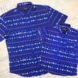 Load image into Gallery viewer, A full representation of both 7-Strong's youth and adult 1776 button down shirts, laid over top each other, against a Declaration of Independence background. Shirt is royal blue with stripes of various Americana icons, including the original 13 colonies and revolutionary war items.
