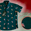 Load image into Gallery viewer, 3/4 full view of the 7-Strong "Oh, Christmas Treat" shirt - a green, christmas sweater-like background with columns of various white Christmas tree shaped cakes with red garland, some whole, some bitten. The shirt is displayed against a red, snowing background with a similar parted cake. Bottom right shows a detail circle highlighting the subtle shirt design.