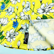 Load image into Gallery viewer, Bottom sweep tag view of the 7-Strong "Late Bloomer" adult button down - a yellow background shirt with white and blue flowers patterned all over it. Shirt is against a blue tropical sky with palm trees in the distance.