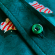 Load image into Gallery viewer, Close up, mid-button view of the 7-Strong "Oh, Christmas Treat" shirt - a green, christmas sweater-like background with columns of various white Christmas tree shaped cakes with red garland, some whole, some bitten. The shirt is displayed against a red, snowing background with a similar parted cake.